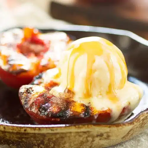 Grilled peaches with cinnamon sugar and melting vanilla ice cream in a skillet