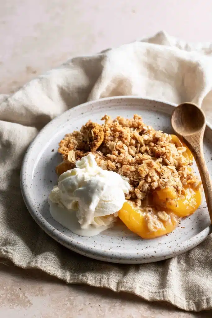 Peach Crisp with Canned Peaches served with vanilla ice cream on a plate